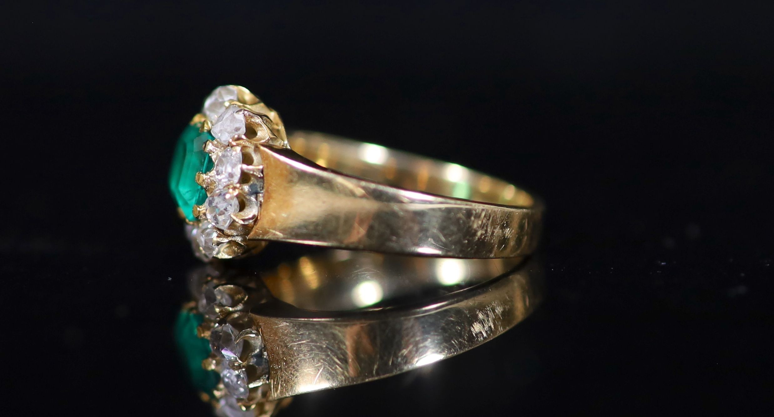 A gold, emerald and old cut diamond set circular cluster ring